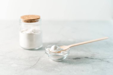 Çevre dostu doğal temizleyiciler, kabartma tozu, limon ve mermer masa zemininde ahşap kaşık dolu kavanoz. Ev yapımı temizlik için organik malzemeler. Sıfır atık