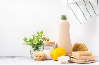 Çevre dostu doğal temizleyiciler, kabartma tozu dolu kavanoz, bulaşık fırçası, limon, çiçekler, beyaz arka planda sabun. Ev yapımı temizlik için organik malzemeler şişeyle temizleniyor. Sıfır atık kavramı, alanı kopyala