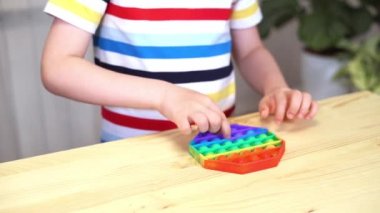 Kid 'in parmaklarını Pop It ile oynarken kapat. Popo kabarcığını esnek, hareketli duyusal oyuncağı çocukların eline ver. Silikon stres giderici. Akıl sağlığı konsepti. Oyuncağa seçici odaklanma