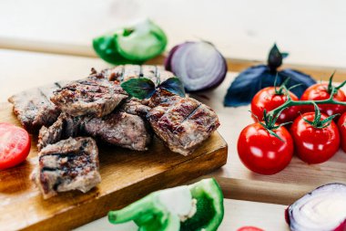 Barbeküyü et, sebze, domates, biber, soğan ve ızgarada kızartılmış fesleğenle kapat. Tahta arkaplan üzerindeki metin için kopyalama alanı olan düz uzandı.