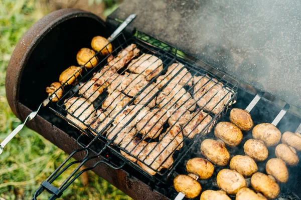 Grilování s masem a houbami smažené na grilu venku na dvorku. Houby na špejlích jsou smažené na dřevěném uhlí — Stock fotografie