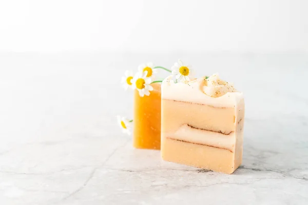 Homemade herbal Soap with chamomile Flowers on white marble background. Zero waste, natural organic bathroom cosmetics. Plastic free life. Ecological skin care, body treatment concept.