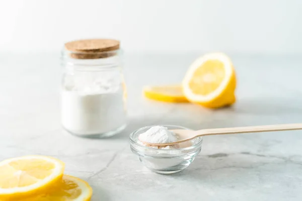 Eco friendly natural cleaners, jar with baking soda, lemon and wooden spoon on marble table background. Organic ingredients for homemade cleaning. Zero waste concept
