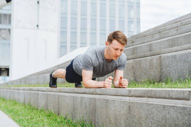 Genç adamın fitness antrenmanı var. Erkek sporcu karın kası egzersizi, spor ve antrenman yapar ve tahta üzerinde durur. İnsanlar ve sağlıklı yaşam tarzı kavramı