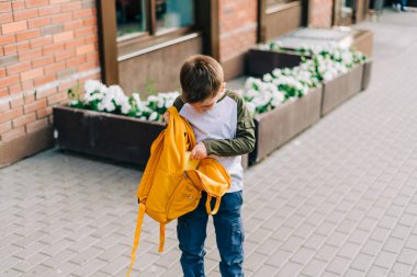 Okula dönelim. Sırt çantalı sevimli çocuk, elinde not defteri ve okula giden eğitim kitapları var. Çantalı bir çocuk. İlkokul öğrencisi derslere giriyor. Şehir caddesinde yürüyen bir çocuk