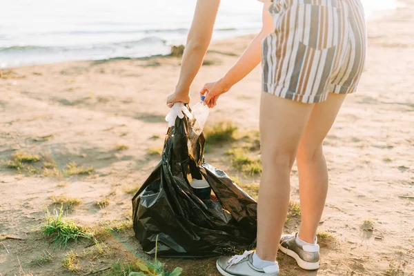 Junge Ehrenamtliche sammeln Müll, Plastikflaschen und Kaffeetassen, säubern Strand und Meer. Frau beim Müllsammeln. Umweltökologisches Verschmutzungskonzept. Tag der Erde — Stockfoto