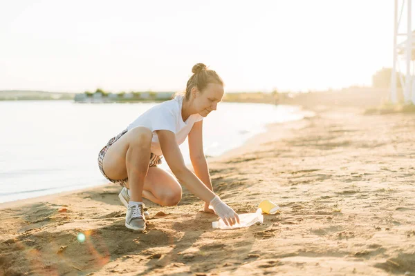 Junge Ehrenamtliche sammeln Müll, Plastikflaschen und Kaffeetassen, säubern Strand und Meer. Frau beim Müllsammeln. Umweltökologisches Verschmutzungskonzept. Tag der Erde — Stockfoto