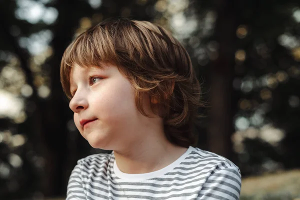 Portrét roztomilého chlapce v lese zamyšleně hledícího z dálky. Modrooký školní den snil v parku. Relaxační venku — Stock fotografie