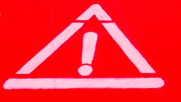 White exclamation mark on vibrant red background, painted with luminescent paint, bike road markings, flash gun artificial light.