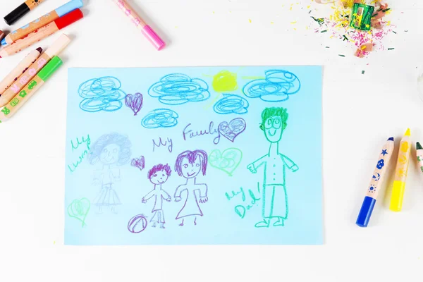 Kids drawing of family and colored pencils on wooden table — Stock Photo, Image