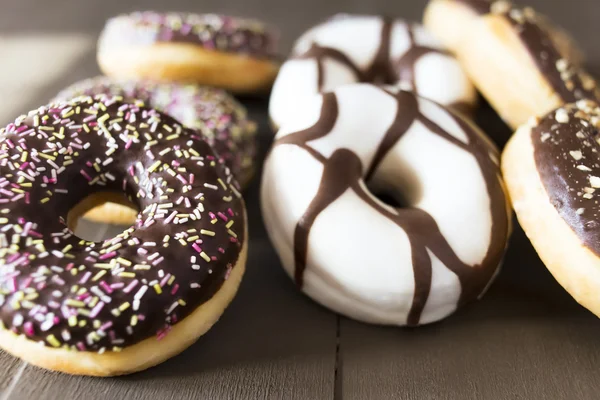 Donuts diferentes em uma mesa de madeira — Fotografia de Stock