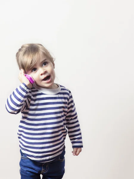 Söt liten flicka talar med en rosa telefon isolerade — Stockfoto