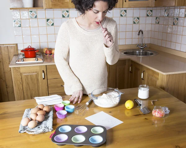 Молодая женщина рассматривает ингредиенты рецепта кексов — стоковое фото