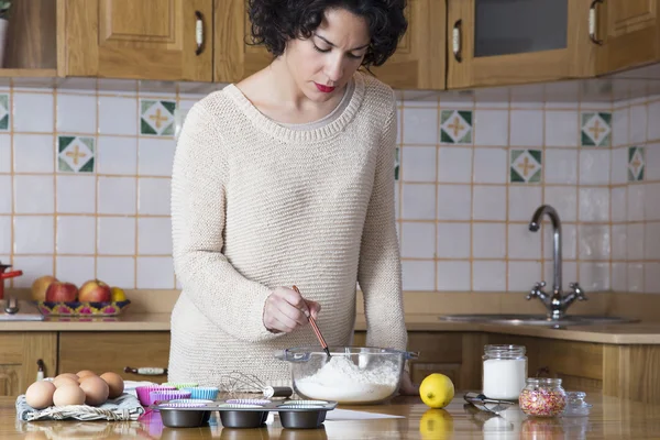 Jeune femme revoyant les ingrédients d'une recette de cupcakes — Photo