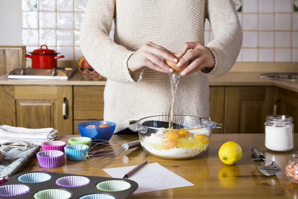 Женщина разбивает яйца, чтобы испечь кексы — стоковое фото