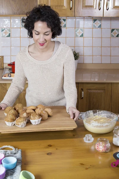 Mulher colocando em uma mesa de madeira uma bandeja com cupcakes e cozido des — Fotografia de Stock