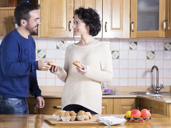 Portrait of man and woman eating homemade sweets in the kitchen — Stock Photo, Image