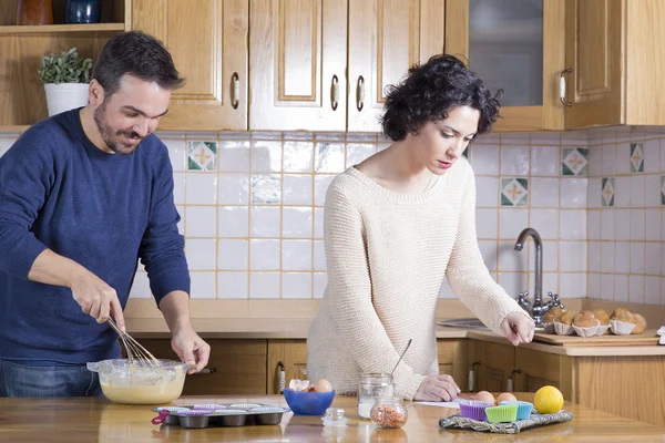 Мужчина взбивает тесто и женщина глядя на рецепт домашнего кекса — стоковое фото