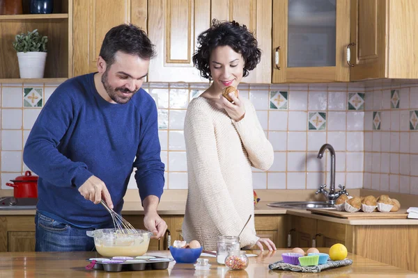 Man whisking dough and woman eating homemade cupcakes — Stock Photo, Image