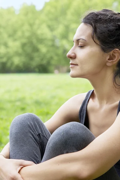 Mulher jovem bonita relaxando em um campo verde — Fotografia de Stock