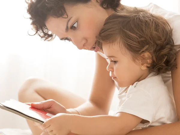 Vrouw en baby meisje lezen op bed — Stockfoto