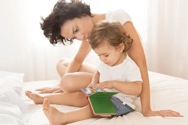 Woman and baby girl reading on bed — Stock Photo, Image