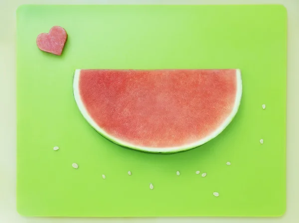 Slice of watermelon without seeds and heart of melon on green tray — Stock Photo, Image