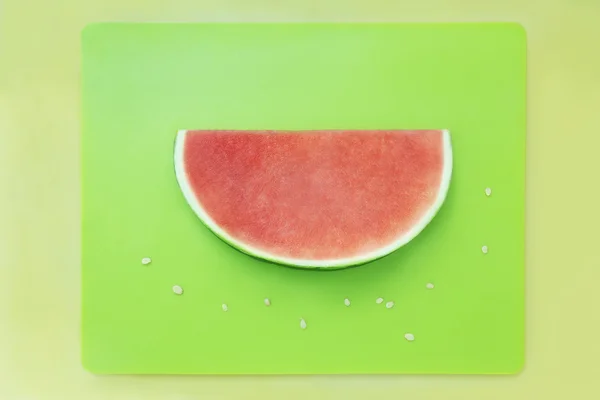 Slice of watermelon without seeds on green tray with yellow back — Stock Photo, Image