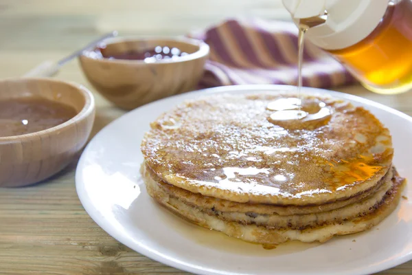 Honig ergießt sich über einen Stapel Pfannkuchen — Stockfoto