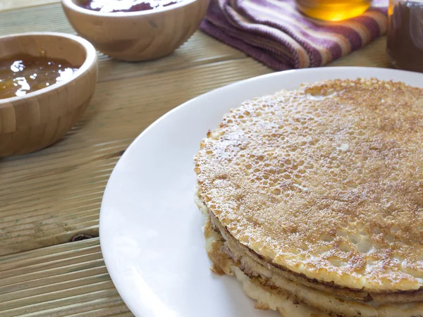 Heerlijke stapel pannenkoeken met chocolade crème, kommen van jam en honing — Stockfoto