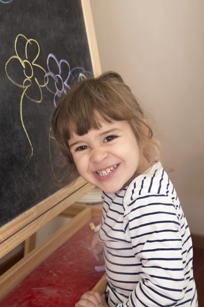 Niña sonriendo orgullosa de su dibujo de flores en el blackboar —  Fotos de Stock