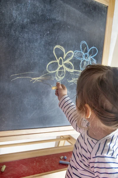 Menina pintando flores no quadro negro — Fotografia de Stock