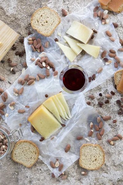 Verre à vin rouge accompagné de fromages variés, d'amandes grillées et de toasts — Photo