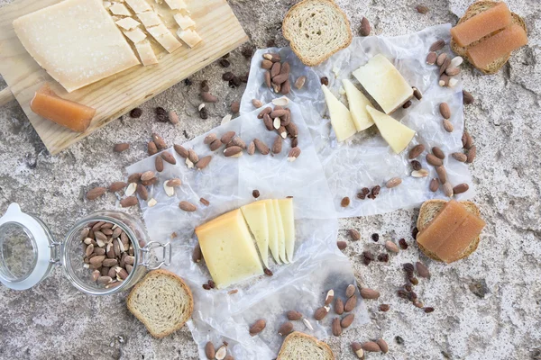 Variété de fromages, amandes grillées, toasts et coings sur table en pierre — Photo