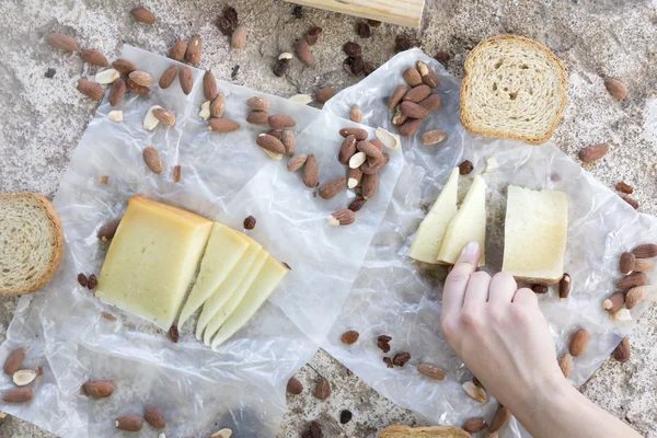 Bir parça peynir, peynir, tost ve badem çerez tutan kadın el