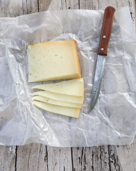Morceaux de fromage avec un couteau sur une vieille planche de bois à la campagne — Photo