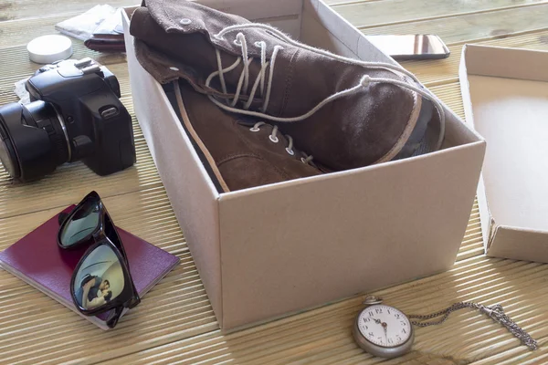 Open box with a pair of boots. Couple giving a kiss to an adventure trip — Stock Photo, Image