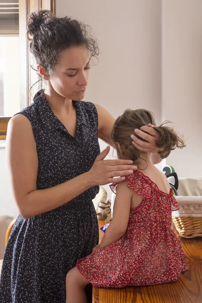 母は彼女の娘の髪をとかす ロイヤリティフリーのストック画像