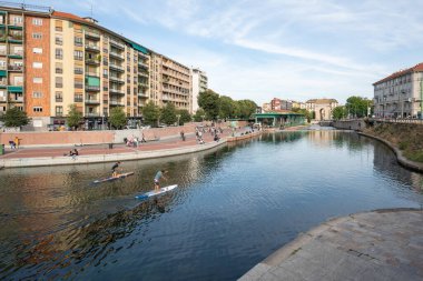 Milan, İtalya-Eylül 29,2020: İnsanlar Naviglio Milano kanalı boyunca yürüyor ve Coronavirus salgını sırasında barlarda dinleniyor (Covid-19) Darsena bölgesi, su üzerinde kano sporu yapan diğer insanlar.