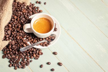 Beyaz kahve, çay kaşığı ve yeşil arka planda kahve çekirdeği. Boşluğu kopyala.