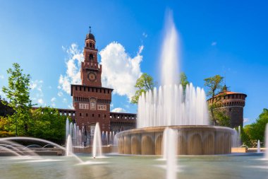 Sforza Kalesi 'nin ana girişi - Sforzesco şatosu ve önündeki çeşme, uzun pozlu fotoğraf, güneşli gün ve gökyüzünde bulutlar, Milan, İtalya
