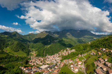 Drone aerial view to the Seriana valley and Orobie Alps with big cloud and blue sky
