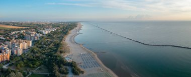 Şemsiyeli ve gazeli kumlu sahil manzarası. Lido Adriano kasabası, Adriyatik kıyısı, Emilia Romagna, İtalya..