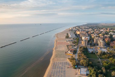 Şemsiyeli ve gazeli kumlu sahil manzarası. Lido Adriano kasabası, Adriyatik kıyısı, Emilia Romagna, İtalya..