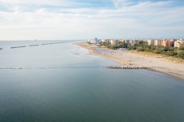 Şemsiyeler, çardaklar ve şehir arka planıyla kumlu kumsalın insansız hava aracı çekimi. Lido Adriano kasabası, Adriyatik kıyısı, Emilia Romagna, İtalya.