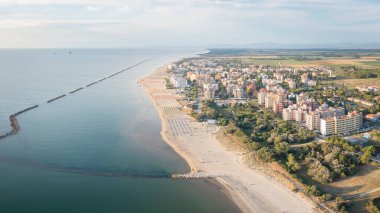Şemsiyeli ve kasabalı kumlu sahilin hava görüntüsü. Lido Adriano kasabası, Adriyatik kıyısı, Emilia Romagna, İtalya.