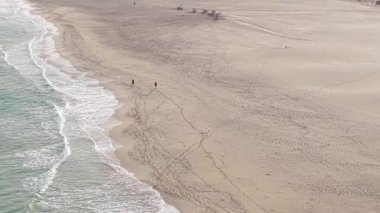 Cape Verde 'deki Boa Vista adasında kumlu sahilde yürüyen iki kişinin güzel manzarası..