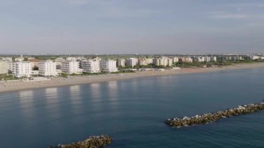 Şemsiyeler, çarşaflar ve arka plan kasabasıyla kumlu kumsalın hava görüntüsü. Lido Adriano şehri, Adriyatik kıyısı, Emilia Romagna, İtalya.