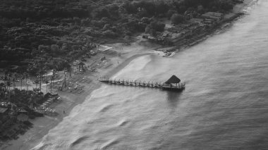 Bayahibe plajı ve Karayip Denizi 'ndeki ahşap bir rıhtımda küçük bir barakanın insansız hava aracı görüntüsü, siyah beyaz fotoğraf, La Romana, Dominik Cumhuriyeti
