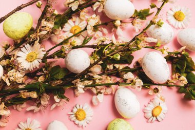 Renkli Paskalya yumurtaları ve pembe arka planda çiçekler. Bahar tatili kavramı